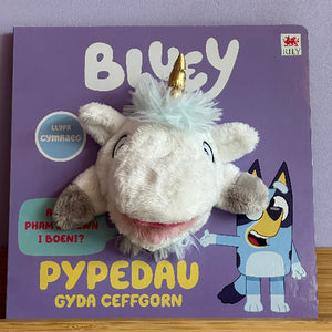 Plush toy resembling a unicorn on a book titled 'Bluey' with a purple cover.