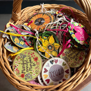 A basket containing various wooden decorations with colorful patterns and text, tied with ribbons.