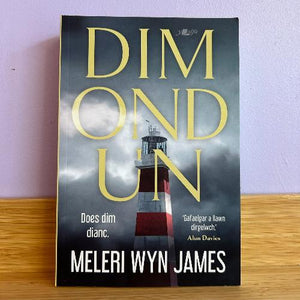 A book cover of 'Dim Ond Un' featuring a lighthouse, with the author's name and the title in Welsh.