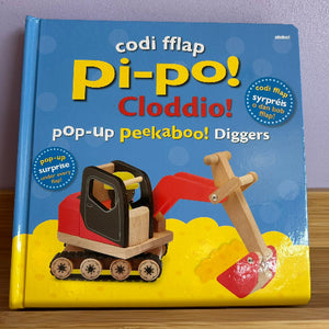 A children's pop-up book titled 'Codi Fflap Pi-po!' featuring a digger on the cover.