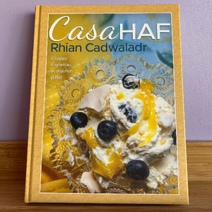 A cookery book cover featuring a close-up image of a dish with dessert and fruits, titled 'Casa Haf' by Rhian Cadwaladr.