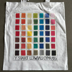 White tote bag with color swatch chart and text on a gray background
