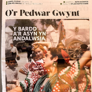Newspaper with a photo of people in traditional clothing and text in Welsh.