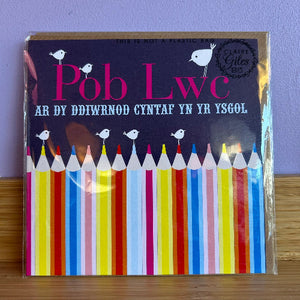 Welsh language good luck card for school featuring  colorful pencils and 'Pob lwc ar dy ddiwrnod cyntaf yn yr ysgol' text on a navy background