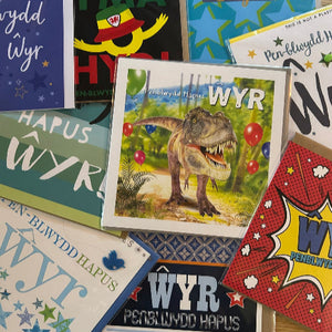 Collection of greeting cards with various designs and text, including a dinosaur illustration.