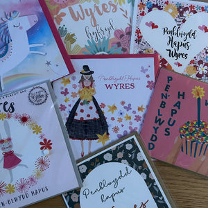 Collection of colorful greeting cards with various designs and text on a wooden surface.