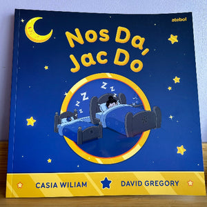 Children's book cover with a blue night sky, moon, and stars, featuring two children in bed.