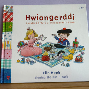 Children's book titled 'Hwiangerddi' with illustrations of two children playing on a blanket.