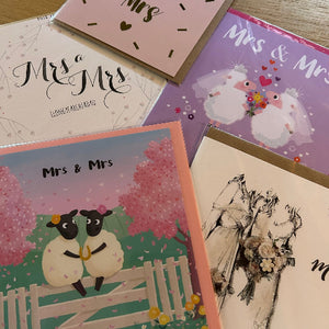 Collection of 'Mrs & Mrs' themed greeting cards on a wooden surface