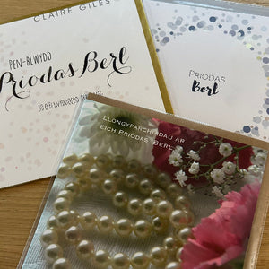 Greeting cards with floral design and pearl necklace on a wooden surface