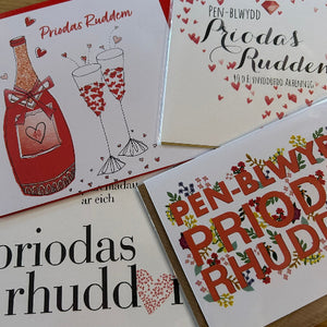 Four greeting cards with different designs and text, featuring a bottle, glasses, and floral elements.