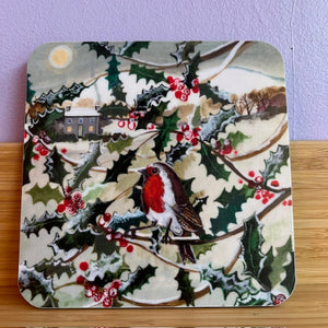 Coaster with a winter scene featuring a robin, holly, and snow-covered landscape on a wooden surface.