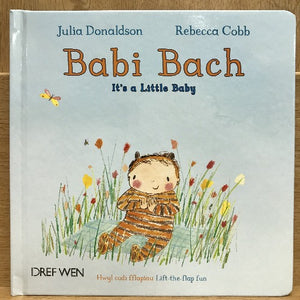 A children's book cover titled 'Babi Bach It's a Little Baby' featuring an illustration of a baby character sitting in a field of flowers with butterflies around.