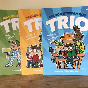 A set of three children's books written by Manon Steffan Ros with illustrations by Huw Aaron, titled 'Trio'. The covers feature colorful illustrations of the main characters, a group of friends, in various adventures.