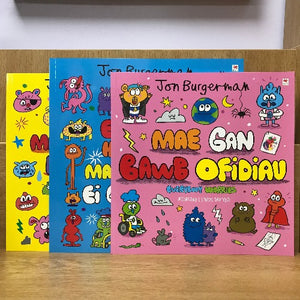 A set of three children's books with colorful covers featuring various characters and text. The titles are in Welsh and the authors and publishers are listed as Jon Burgerman and Rily.