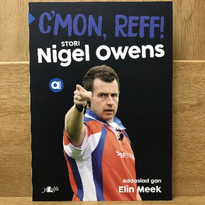 A book cover featuring the title 'C'mon Reff! Stori Nigel Owens' with a photograph of Nigel Owens in a rugby referee uniform pointing forward.