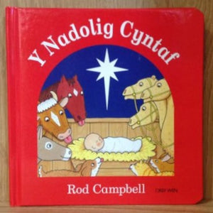 A red book titled 'Y Nadolig Cyntaf' featuring illustrations of the nativity scene with Mary, Joseph, baby Jesus, a donkey, and a horse.
