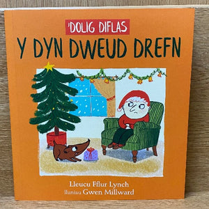 Book cover of 'Dolig Diflas y Dyn Dweud Drefn' featuring a cartoon illustration of a grumpy character in a red hat, sitting in a chair with a scowl on their face, with a decorated Christmas tree.