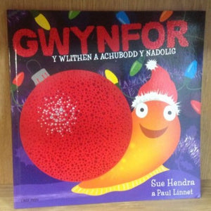 A book cover featuring a cartoon image of a slug with a Santa hat and a Christmas tree in the background, with the title 'GWYNFOR Y WLITHEN A ACHUBOD Y NADOLIG'.