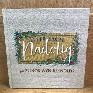 A book cover featuring a Christmas-themed design with text 'Llyfr Bach Nadolig' by Elinor Wyn Reynolds.