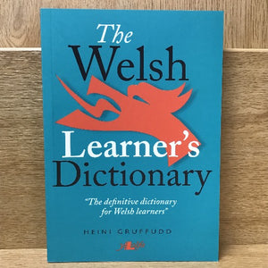 The image shows a cover of a book titled 'The Welsh Learner's Dictionary' by Heini Gruffudd. The cover has a green background with a red silhouette of a dragon and white text.