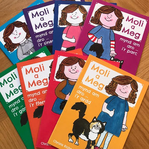 A collection of children's books with colorful covers, titled 'Moli a Meg' with illustrations of a girl and a cat on the front.
