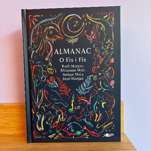 Book titled 'Almanac O Fis i Fis' with colorful illustrations on a wooden surface.