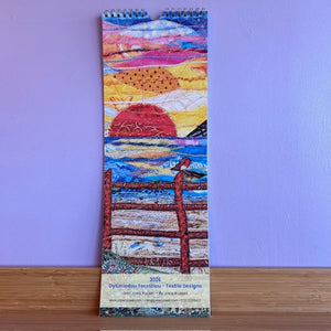 Vertical calendar with a colorful design of a sunset and fence on a purple background
