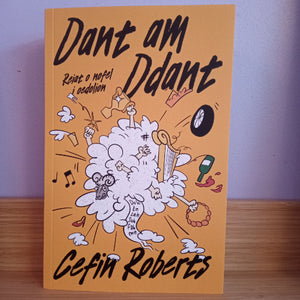 Book cover of 'Dant am Ddant' by Cefin Roberts with cartoon illustrations on a wooden surface.