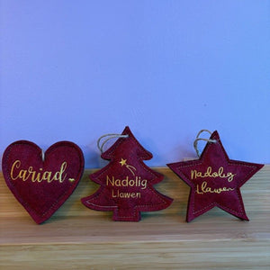 Red Christmas ornaments with gold text on a wooden surface and blue background