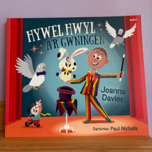 Children's book titled 'Hywel Hwyl Ar Gwningen' with a colorful illustration of a magician on the cover.