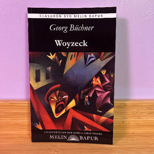 Book cover of 'Woyzeck' by Georg Büchner on a wooden surface with a purple background
