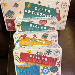 Stack of educational toy boxes with colorful graphics and text on a wooden surface