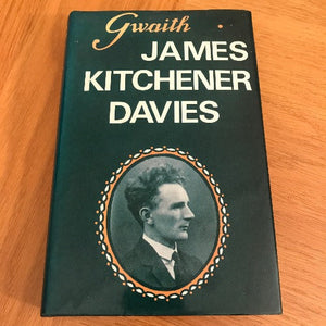 Book cover with portrait of a man and text 'Gwaith James Kitchener Davies' on a wooden surface