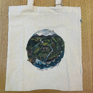 Tote bag with a circular design of a landscape on a wooden surface