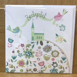 Greeting card with floral design and church illustration on a wooden surface