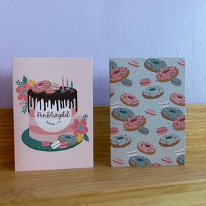 Two greeting cards on a wooden surface with a light blue wall background.