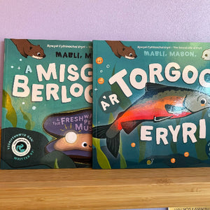 Two children's books with underwater-themed covers on a wooden surface.