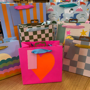 Colorful gift bags with various designs on a wooden surface