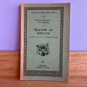 Vintage book titled 'Dafydd ap Gwilym' with decorative cover on a wooden surface and purple wall background