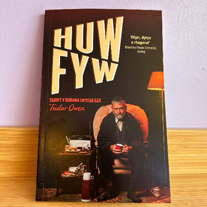Book cover of 'HUW FYW' with a man sitting in an armchair holding a cup.