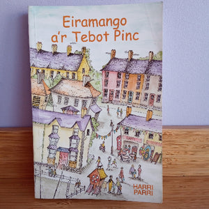 Book cover with colorful illustration of a village and text on a wooden surface.