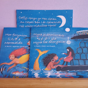 Three children's books on a wooden surface with a purple background