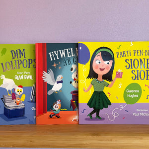 Three children's books with colorful covers and illustrations on a wooden surface.