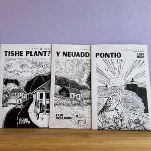 Three books with black and white illustrations on a wooden surface against a purple wall.