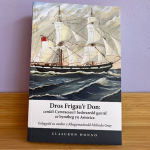 Book cover with a ship illustration on a wooden surface and purple wall background
