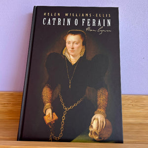 Book titled 'Catrin O Ferain' by Helen Williams-Ellis on a wooden surface with a purple background