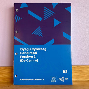 A three-ring binder workbook titled 'Dysgu Cymraeg Canolrdd Fersiwn 2 (De Cymru)'. The cover is blue and dark purple with geometric triangle patterns and white text.
