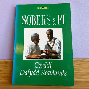 A green paperback book titled 'SOBERS a FI' by Cerddi Dafydd Rowlands, featuring a photo of two men shaking hands on the cover.