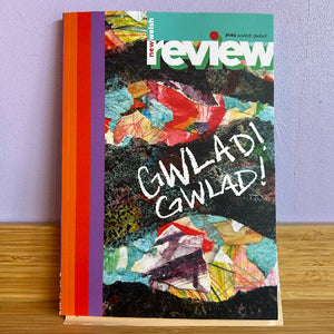 New Welsh Review magazine, issue #140, standing upright on a wooden surface against a light purple wall. The cover features a colorful abstract collage with the title 'new york review' at the top and the text 'GWLAD! GWLAD!' in white across the center.